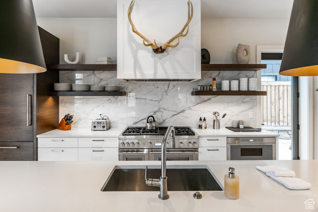 Kitchen with white cabinetry, backsplash, stainless steel appliances, and sink