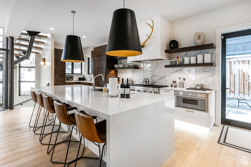 Kitchen with appliances with stainless steel finishes, pendant lighting, a kitchen island with sink, and a wealth of natural light