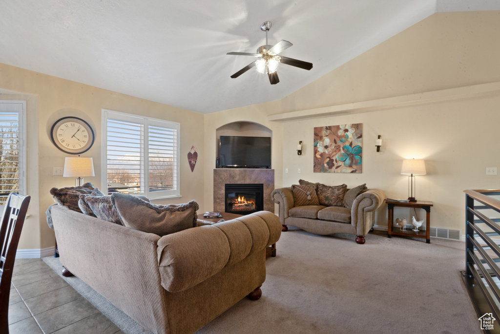 Carpeted living room with vaulted ceiling, ceiling fan, and a fireplace