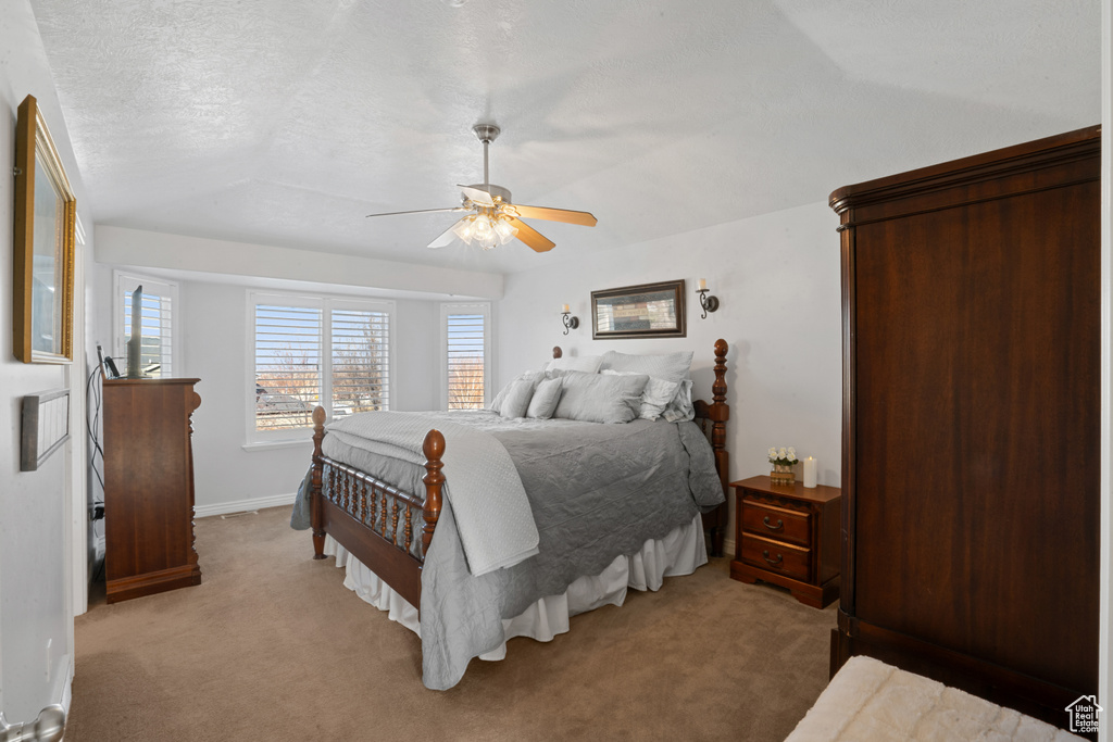 Bedroom featuring a textured ceiling, light carpet, and ceiling fan