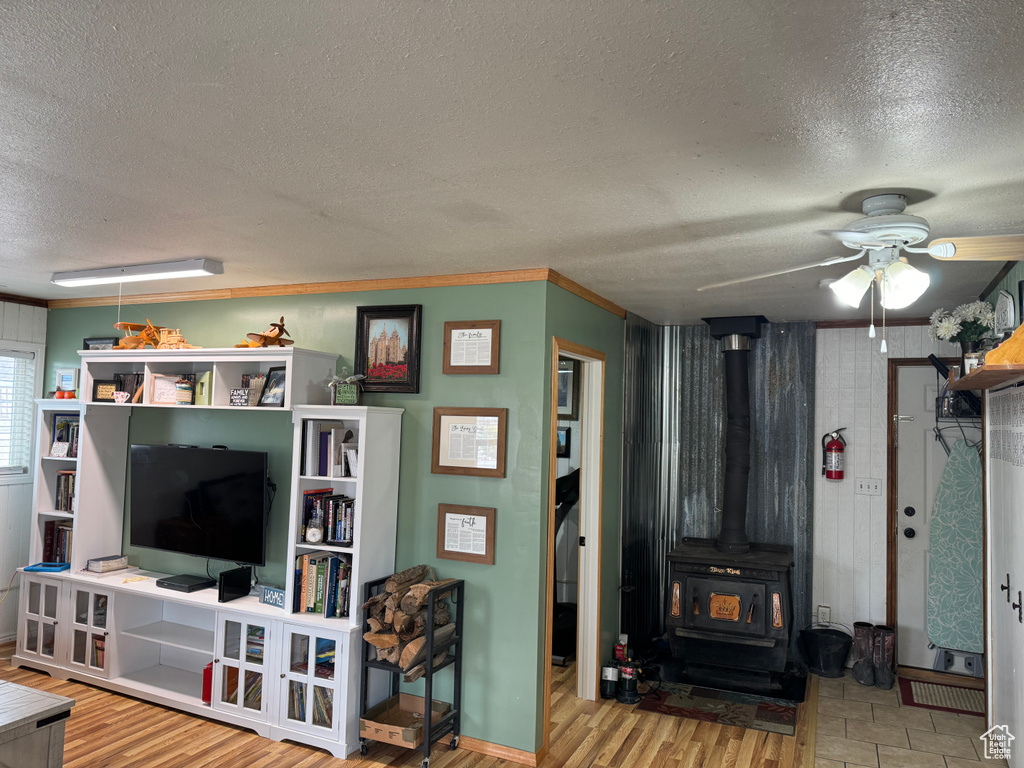Living room with light wood-type flooring, a wood stove, and a textured ceiling