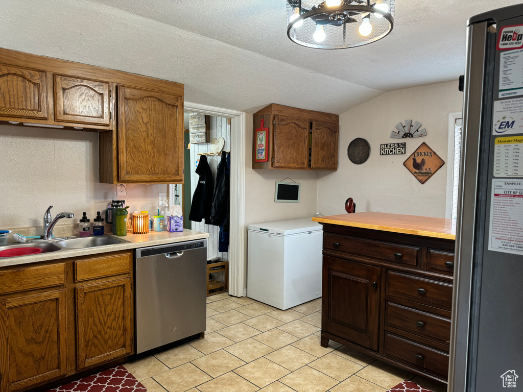 Kitchen featuring dishwasher, lofted ceiling, refrigerator, and sink