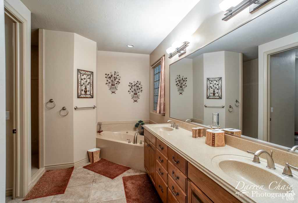 Bathroom with double sink, a bath to relax in, tile flooring, and vanity with extensive cabinet space