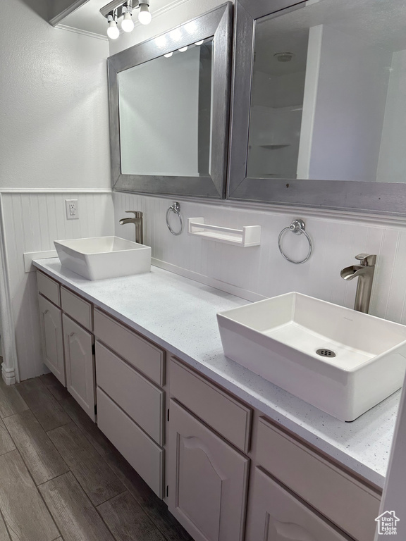 Bathroom with dual bowl vanity, hardwood / wood-style flooring, and crown molding