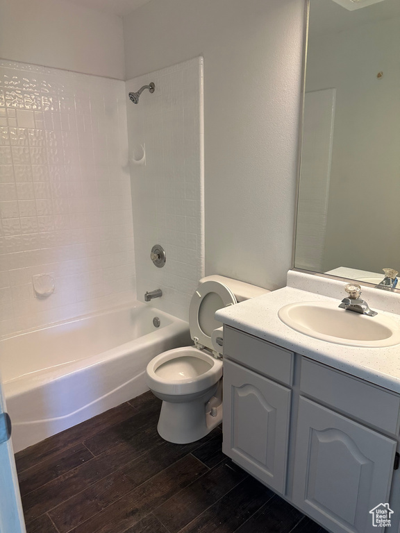 Full bathroom featuring hardwood / wood-style flooring, shower / washtub combination, toilet, and vanity