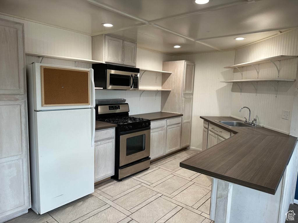 Kitchen with sink, white cabinets, light tile floors, butcher block countertops, and appliances with stainless steel finishes