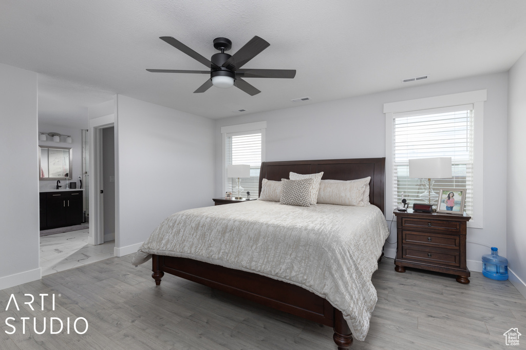 Bedroom with ensuite bathroom, light hardwood / wood-style floors, and ceiling fan