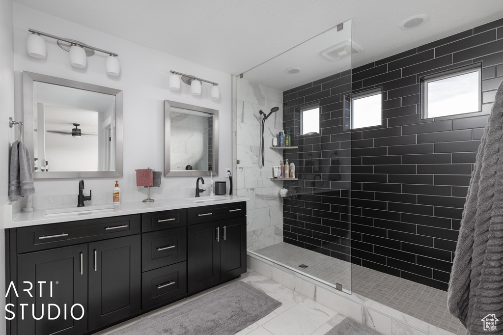 Bathroom with dual bowl vanity, a tile shower, and tile flooring