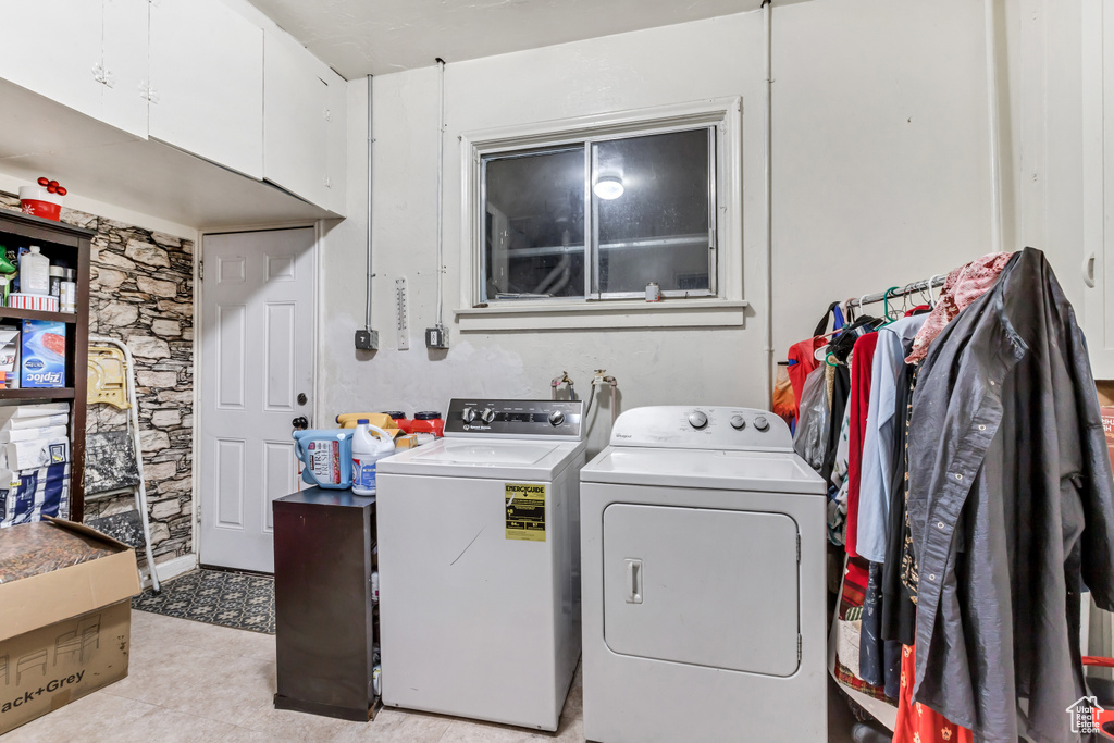 Laundry room with light tile floors, cabinets, and washing machine and clothes dryer