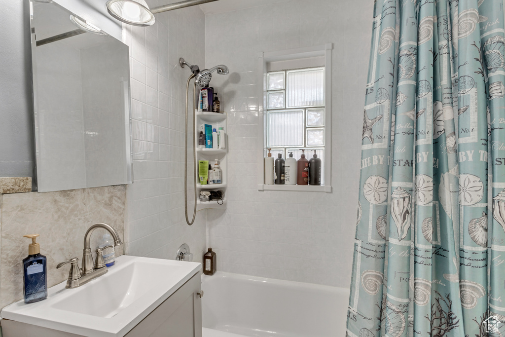 Bathroom featuring vanity, shower / bath combination with curtain, and tile walls