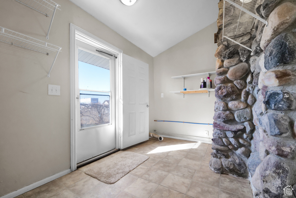 Doorway to outside featuring lofted ceiling and light tile floors