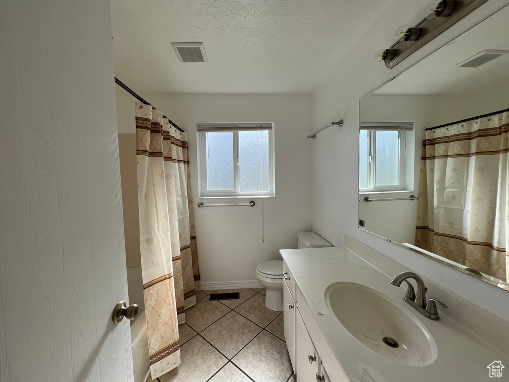 Bathroom featuring a wealth of natural light, toilet, tile flooring, and oversized vanity