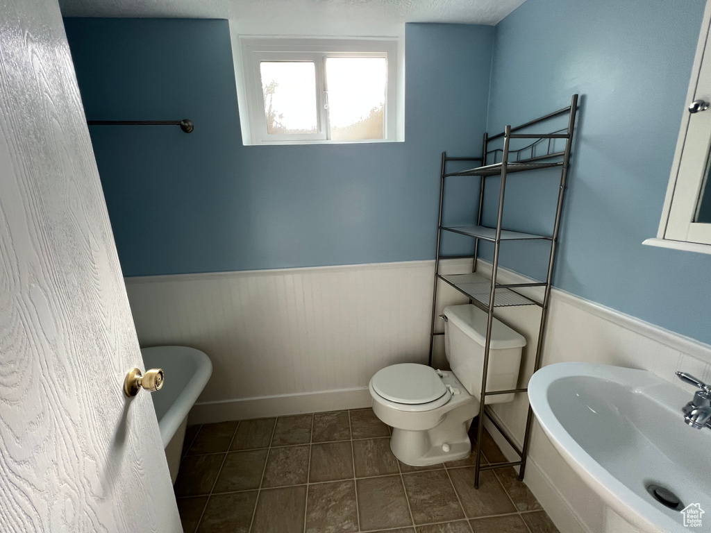 Bathroom with toilet, tile flooring, sink, and a bathtub