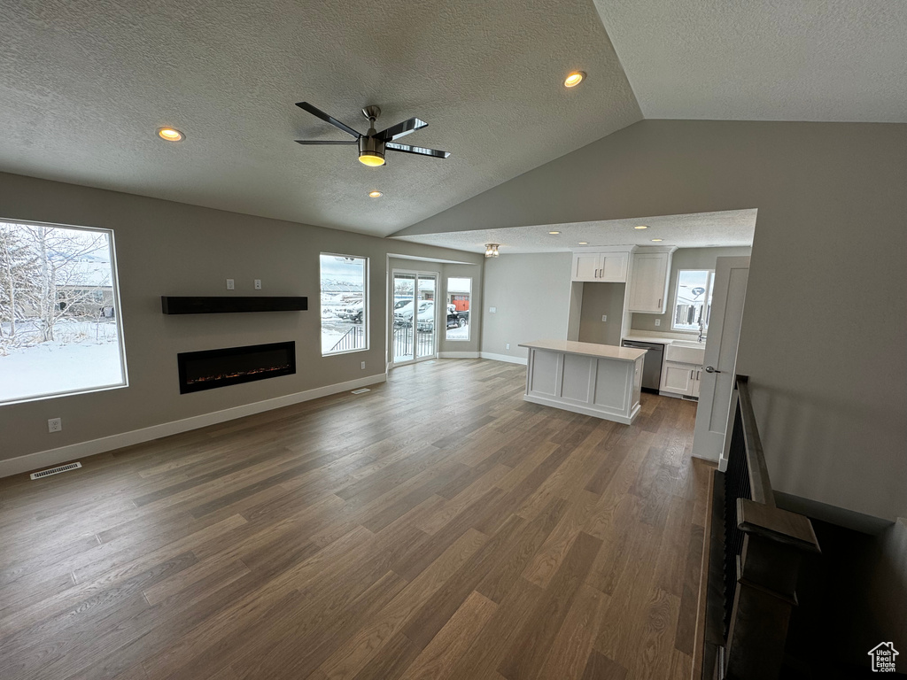 Unfurnished living room featuring dark hardwood / wood-style floors, a wealth of natural light, and ceiling fan