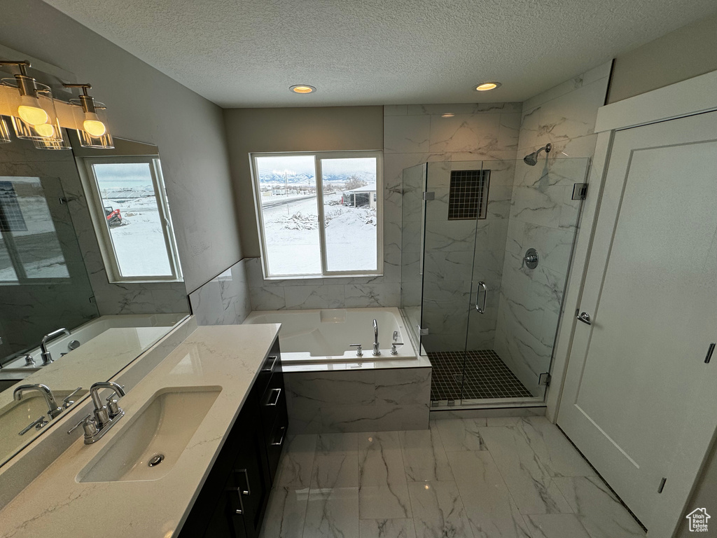 Bathroom featuring a textured ceiling, plus walk in shower, large vanity, and tile floors