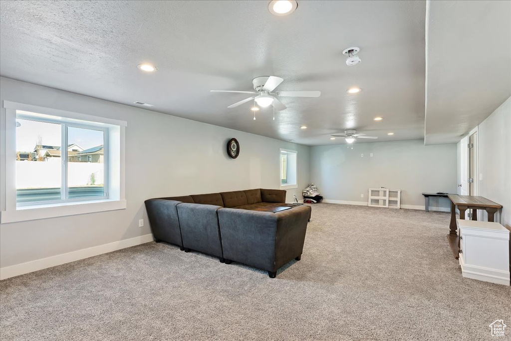 Carpeted living room with a textured ceiling and ceiling fan