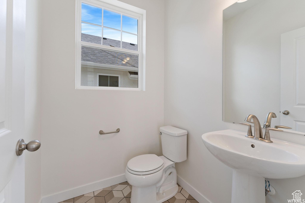 Bathroom featuring toilet, tile flooring, and sink