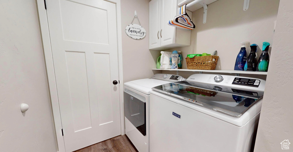 Clothes washing area featuring dark hardwood / wood-style floors, cabinets, and washer and dryer