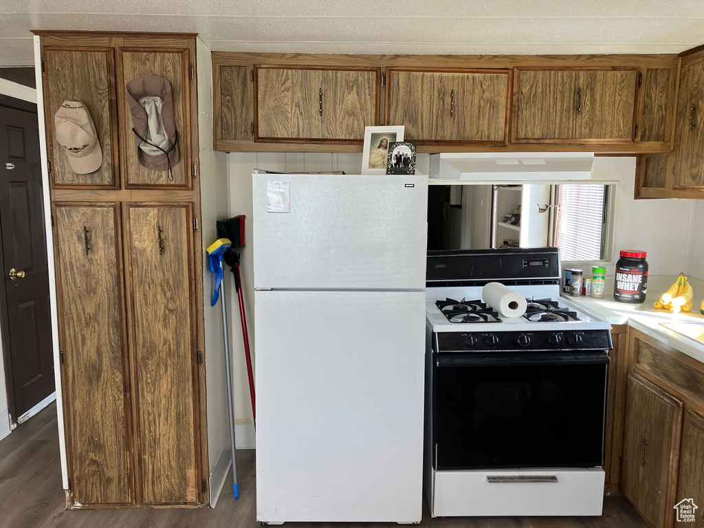 Kitchen with dark hardwood / wood-style floors, white appliances, and range hood