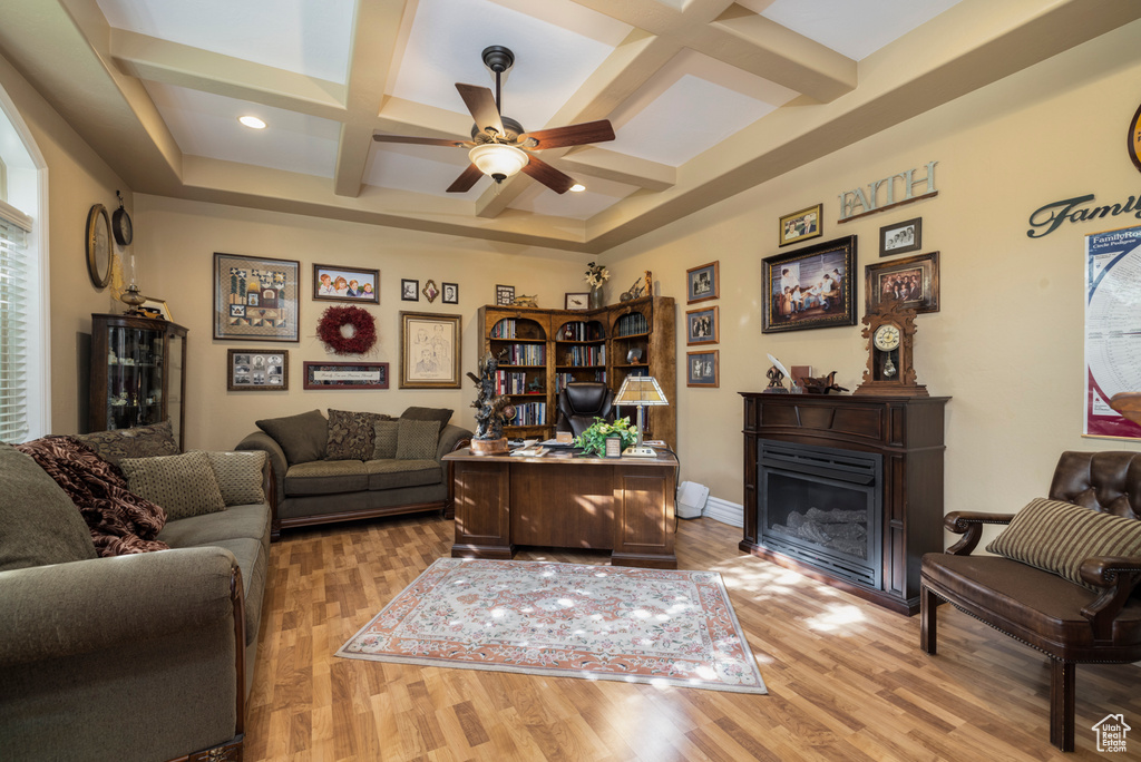 Living room featuring coffered ceiling, ceiling fan, light hardwood / wood-style flooring, and beamed ceiling