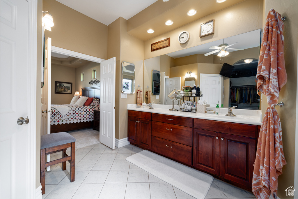 Bathroom featuring tile flooring, vanity with extensive cabinet space, dual sinks, and ceiling fan