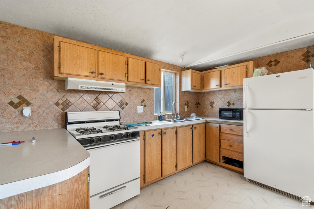 Kitchen featuring backsplash, vaulted ceiling, sink, white appliances, and light tile flooring