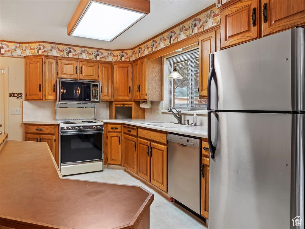 Kitchen featuring appliances with stainless steel finishes, sink, and light tile flooring