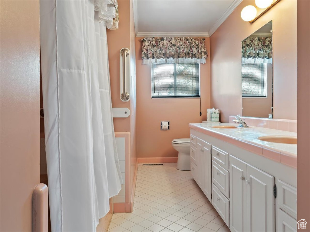 Bathroom featuring a wealth of natural light, ornamental molding, tile flooring, and toilet