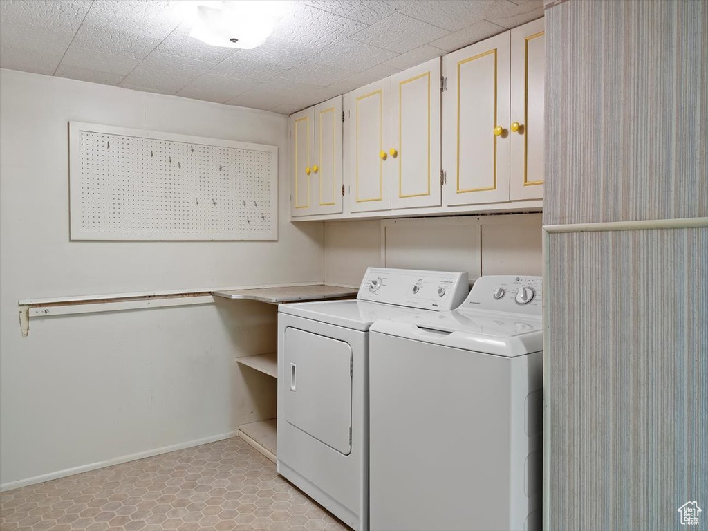 Washroom with cabinets, washer and clothes dryer, and light tile floors