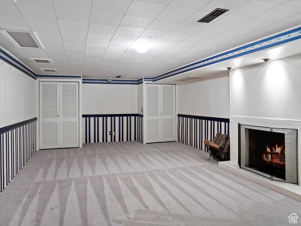 Basement with light colored carpet and a fireplace