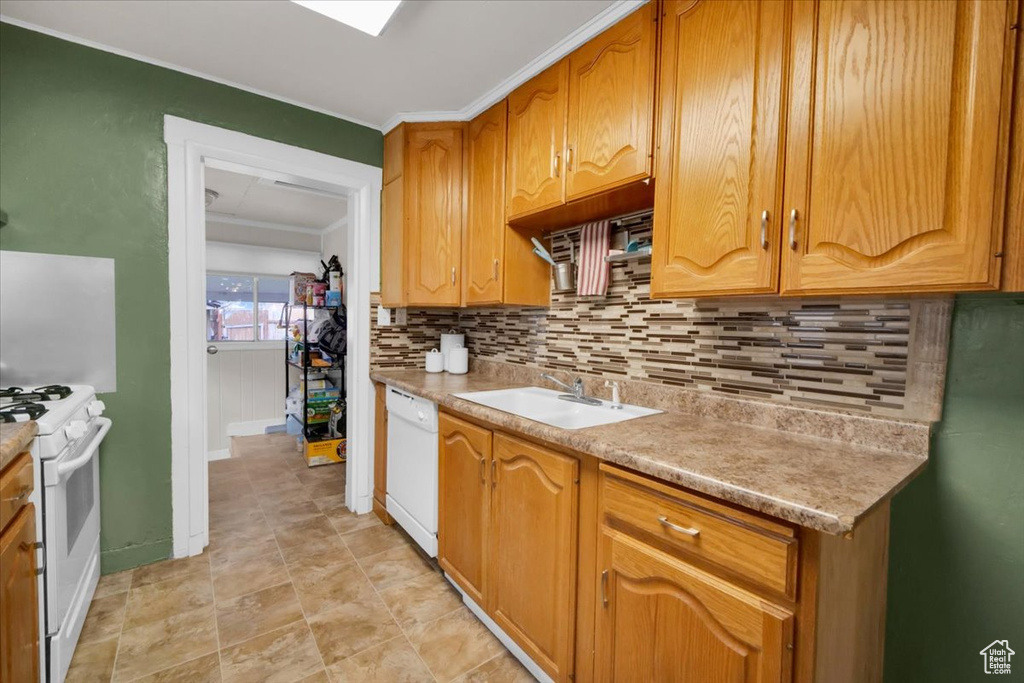 Kitchen featuring tasteful backsplash, light tile floors, ornamental molding, white appliances, and sink