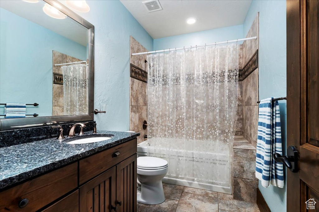Full bathroom with shower / bath combination with curtain, toilet, vanity, and tile floors