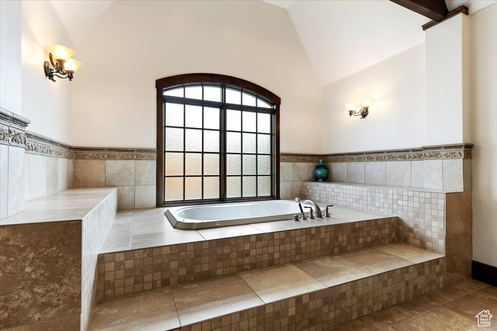 Bathroom with high vaulted ceiling, tile flooring, and tiled tub