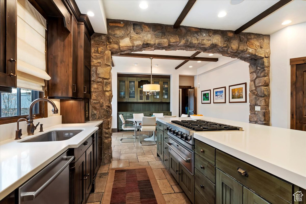 Kitchen featuring decorative light fixtures, stainless steel dishwasher, light tile floors, beam ceiling, and sink