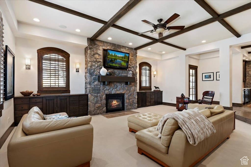 Carpeted living room featuring a stone fireplace, a wealth of natural light, coffered ceiling, and beam ceiling