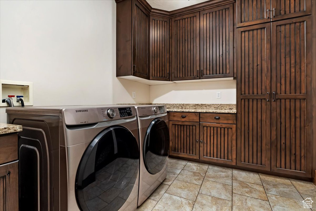 Clothes washing area with cabinets, washer and dryer, washer hookup, and light tile floors