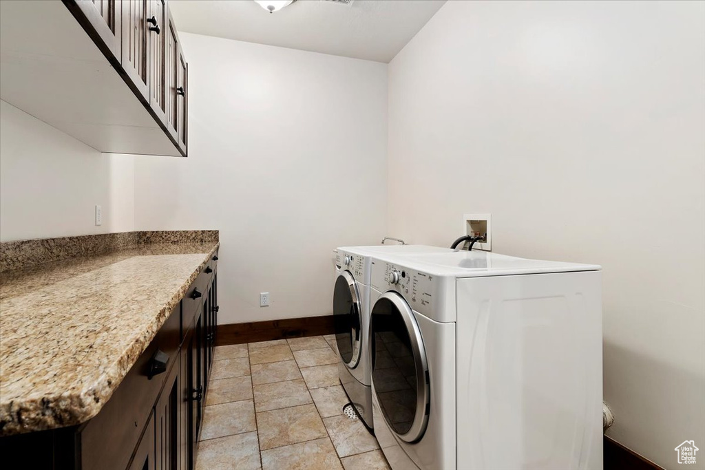Laundry area featuring cabinets, separate washer and dryer, light tile floors, and hookup for a washing machine