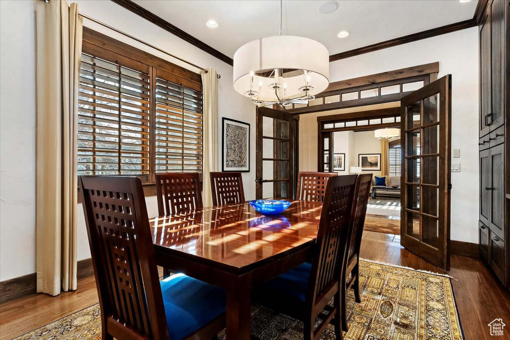 Dining space featuring crown molding, french doors, an inviting chandelier, and dark hardwood / wood-style floors