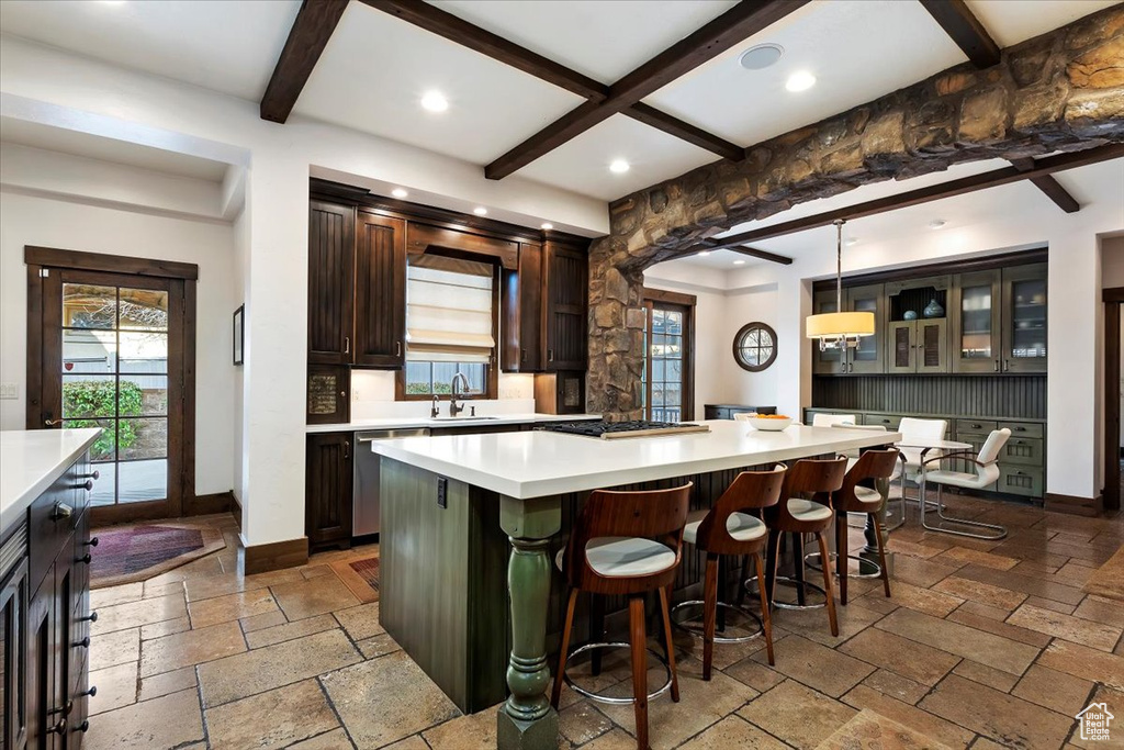 Kitchen featuring dark brown cabinetry, tile floors, a center island, and beam ceiling