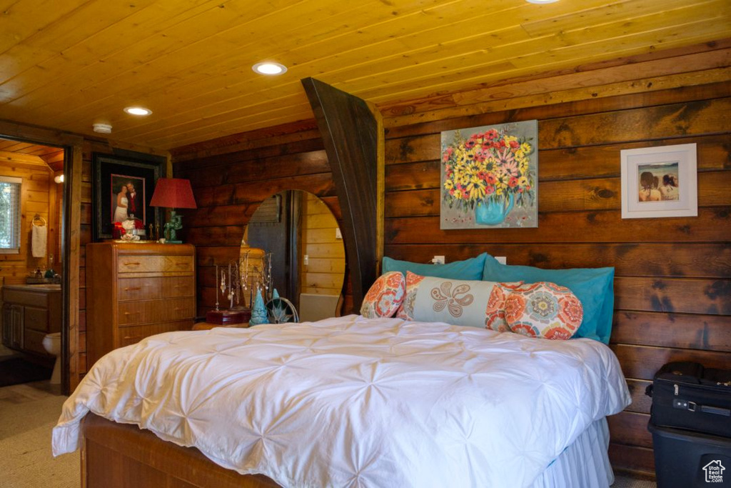 Bedroom featuring connected bathroom, log walls, and wooden ceiling