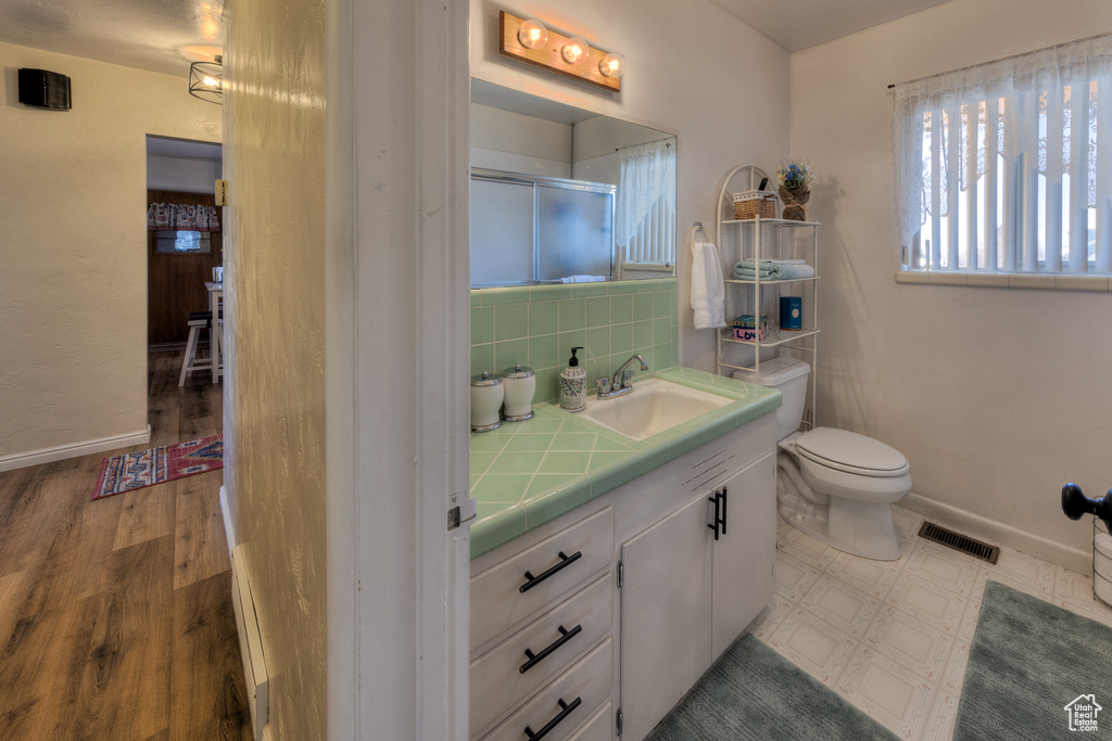 Bathroom featuring hardwood / wood-style floors, toilet, tasteful backsplash, and oversized vanity