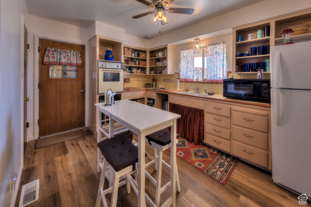 Kitchen featuring sink, light hardwood / wood-style flooring, white appliances, and ceiling fan