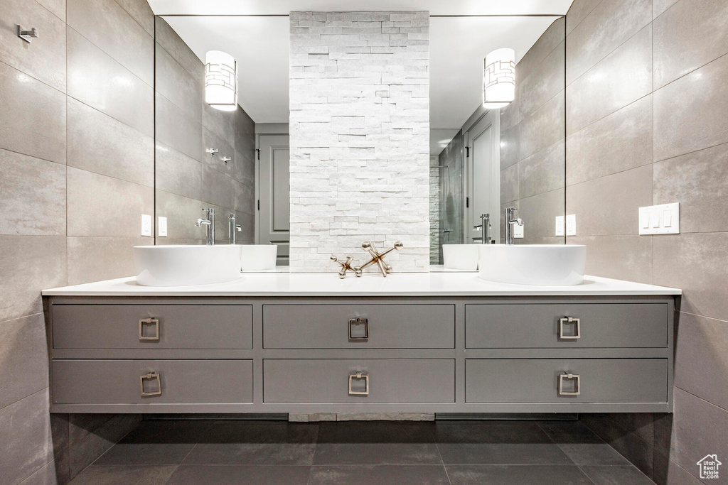Bathroom with dual bowl vanity, tile walls, and tile floors