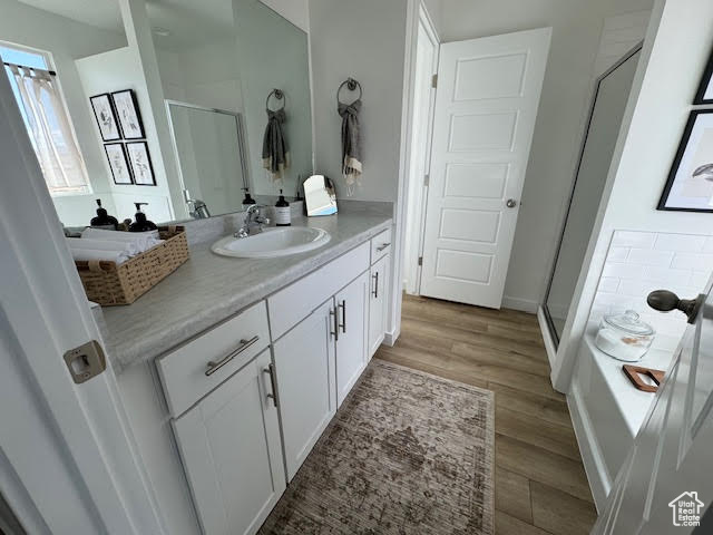 Bathroom with a shower with door, hardwood / wood-style flooring, and vanity