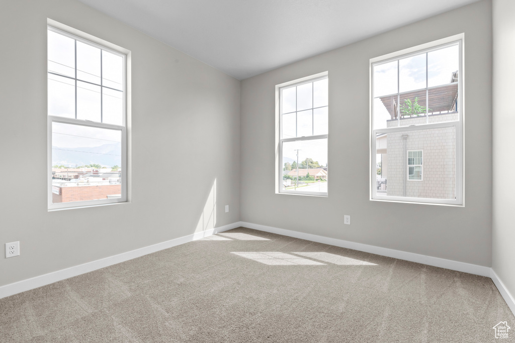 Empty room with light colored carpet and plenty of natural light