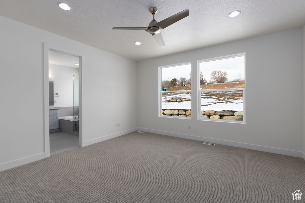 Unfurnished bedroom featuring connected bathroom, light colored carpet, and ceiling fan