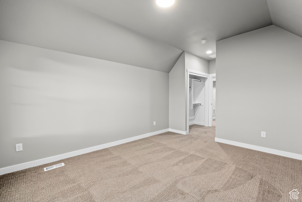 Additional living space with light carpet and lofted ceiling