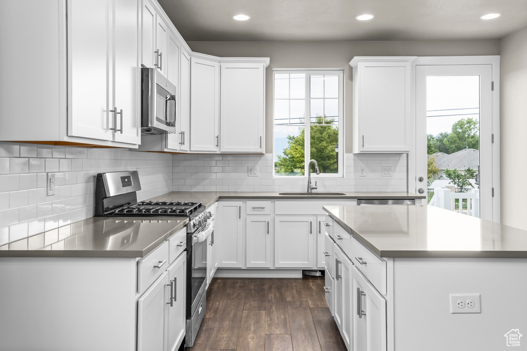 Kitchen with appliances with stainless steel finishes, dark hardwood / wood-style flooring, white cabinetry, and sink