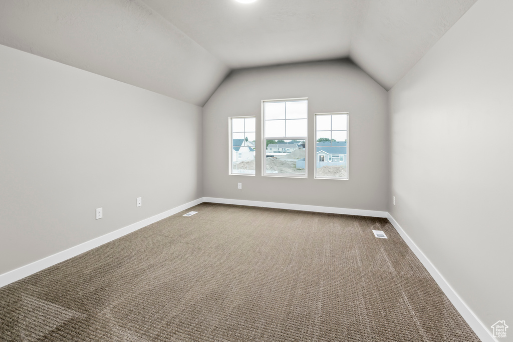 Empty room featuring vaulted ceiling and carpet