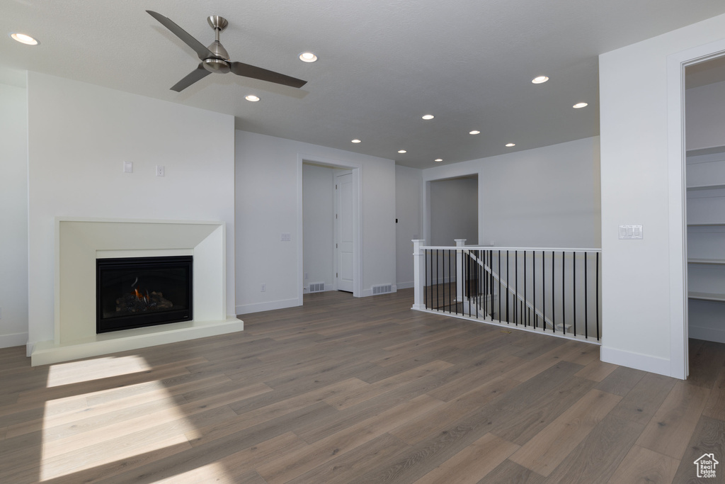 Unfurnished living room with ceiling fan and dark wood-type flooring